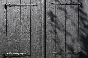 Black tarred doors with old hinges.