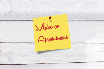 Yellow paper note with text Make an Appointment on wooden background