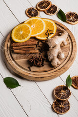 Fresh orange slices with spices and ginger root on wooden plate