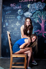 Obraz na płótnie Canvas back to school after summer vacations, two teen real girls in classroom with blackboard painted together, lifestyle people concept