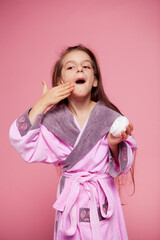 cute girl dressed in a terry bathrobe applies face cream