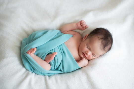 New born baby girl sleeps at home and smiling in a dream. Cute little kid's portrait
