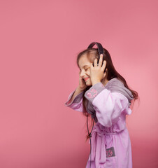 a girl dressed in a terry dressing gown listens to music in big black headphones