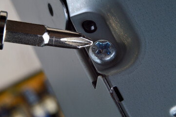 disassembling a metal computer case with a small screwdriver. close-up