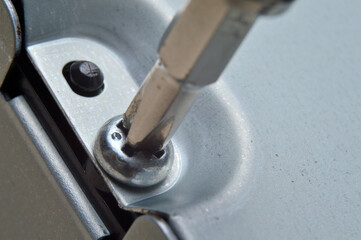 disassembling a metal computer case with a small screwdriver. close-up