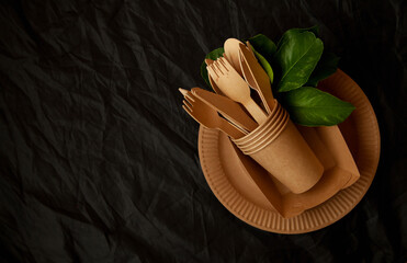 disposable eco tableware made of cardboard spoon fork knife. Place for signature on a black background