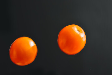 Falling tomatoes isolated on a black background, freeze in motion