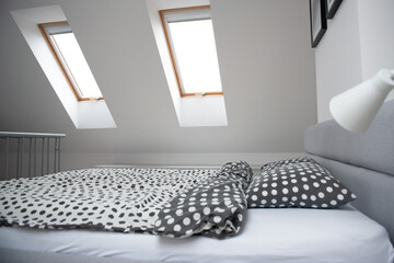 Modern monochrome design home interior of bedroom room in mansard with wooden bed and elegant accessories.