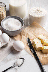 Ingredients and tools for home baking on a culinary background. Eggs, flour, milk, sugar, butter, almond flakes, syrup on the kitchen table. Concept of preparation for baking. Homemade pastry. Cooking