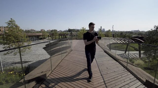 Man walking on the unusual construction of Tyufeleva roshcha. Action. Male photographer in black clothes with a professional camera walking in a modern park.