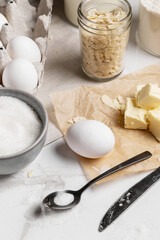 Ingredients and tools for home baking on a culinary background. Eggs, flour, milk, sugar, butter, almond flakes, syrup on the kitchen table. Concept of preparation for baking. Homemade pastry. Cooking