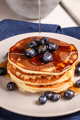 American breakfast. Stack of homemade american pancakes with fresh berry and pouring maple syrup on a white background. Fresh blueberries. Food photo. Breakfast photo. Recipe. Fluffy. Close up view