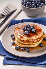 American breakfast. Stack of homemade american pancakes with fresh berry and pouring maple syrup on a white background. Fresh blueberries. Food photo. Breakfast photo. Recipe. Fluffy. Close up view