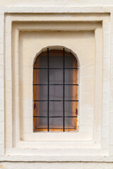 Fototapeta na wymiar Small window with metal grate in an ancient stone wall