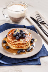 American breakfast. Stack of homemade american pancakes with fresh berry and pouring maple syrup on a white background. Fresh blueberries. Food photo. Breakfast photo. Recipe. Fluffy. Close up view