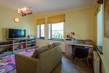 Contemporary interior in yellow tones of kid`s room in luxury apartment. Soft couch. Wooden furniture.