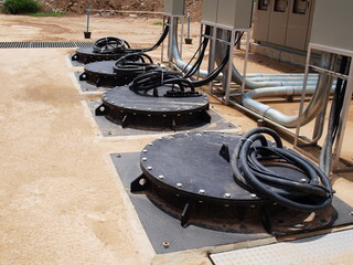 Pumps in the sewage pumping station. Electrical wires and black metal cover of Submersible Pump on outdoor concrete tank. For drainage of municipal sewage or rainwater. Selective focus