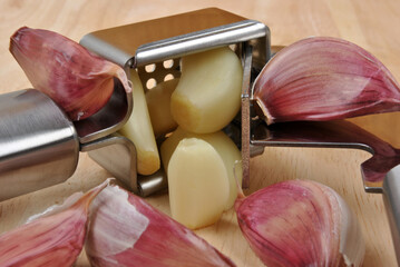 organic fresh garlic and garlic press on a timber board