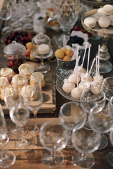 Wedding buffet and decorations. Sweets, cookies, berries and fruits. Macaroons. Wooden cart on grass. Nature. Pastel colors. Dishes and serving. Catering