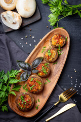  Baked stuffed mushrooms on a wooden plate top view, vertical photo