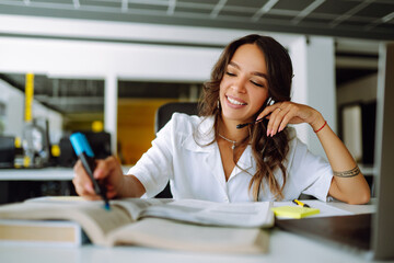 Young  woman wearing headphones using laptop  watching webinar or doing video chat by webcam....