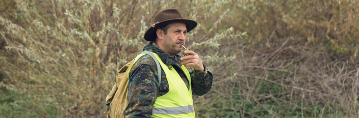 Fototapeta premium Duck hunter with shotgun walking through a meadow.