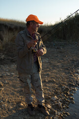 Fisherman standing on the riverside and trying to catch a fish. Sport, recreation, lifestyle.