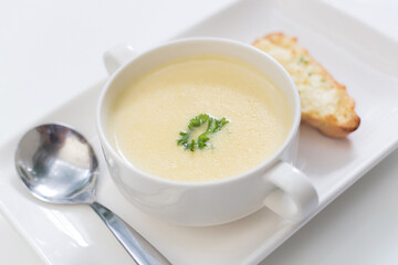 Delicious corn soup In a white bowl served with bread.