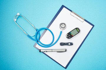 clipboard with white blank sheets of paper, stethoscope, glucose meter, lancet and syringe pen with...