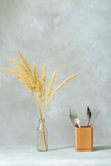 View of serving. cutlery in a wooden vase. stylish rustic background and decorated bottle with dry reed flowers