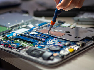 Mano sujetando un destornillador arreglando la placa base de un ordenador