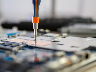 Fototapeta premium Mano sujetando un destornillador arreglando la placa base de un ordenador