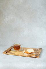 Couple of pieces of fresh muffin chopped and cup of tea breakfast on a wooden serving board  lie stylish rustic background