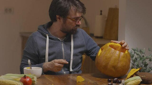 Young man carving face on pumpkin for Halloween
