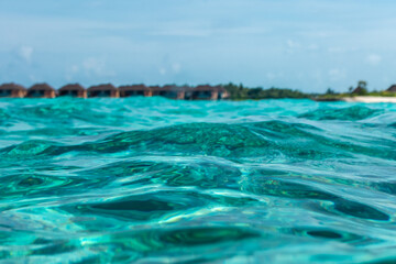 Fototapeta na wymiar Tropical villas on beach shot from water waves of Indian ocean on Maldive isalnds