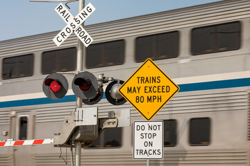 High speed train warning sign at railroad crossing with motion blur of train in background. Concept...