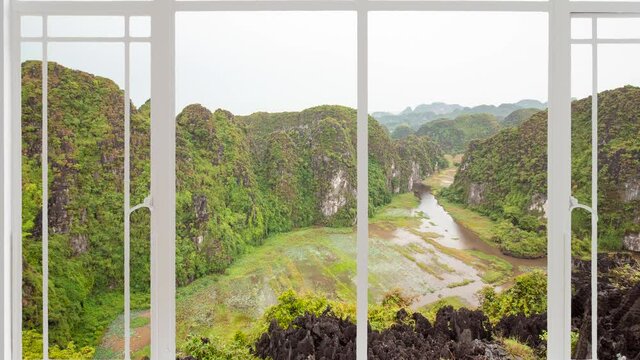 Tam Coc landscape as seen from a white window while birds are flying. It is seen green and gold rice field in background with balck mountain in close up with temple above it. Near Ninh Binh, Vietnam 