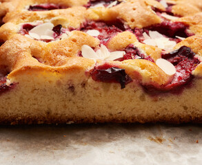 baked slices of sponge cake with plums on brown paper