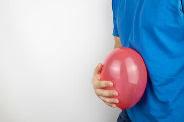 Bloating and flatulence concept. The man holds a red balloon near the abdomen, which symbolizes gas...