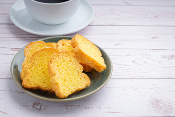 Crispy butter toast and a white coffee cup on wooden table with space for text