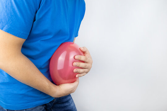 Bloating and flatulence concept. The man holds a red balloon near the abdomen, which symbolizes gas problems. Intestinal tract and digestive system
