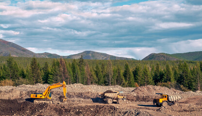 Excavator loads mountain soil into the body of a mining dump truck and then transports the load. Extraction of minerals in the mountainous region of Eastern Siberia © Letopisec
