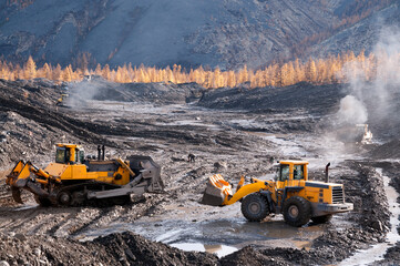 Open pit mining (natural gold) in mountainous areas. A bulldozer collects a pile of mountain soil....