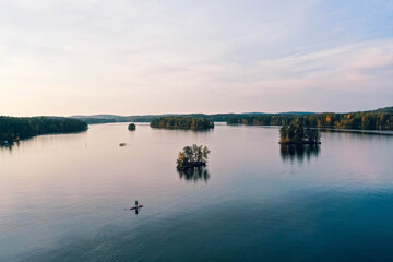 Drone shot of a person paddle boarding in autumn lake views in Heinola, Finland