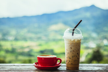 Hot cappuccino coffee cup and Ice cappuccino coffee on wooden table with blur natural mountain view background.