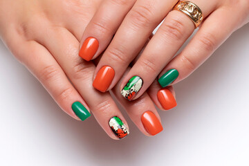 Autumn orange, green, black, yellow cracked manicure on short square nails close-up on a white background. Gel nail design.
