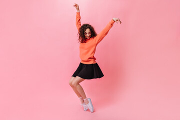 Happy girl in black skirt and sweater posing on pink background