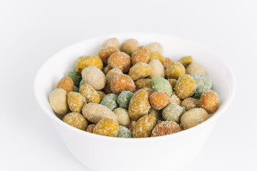 Salted peanuts covered with glaze in a ceramic bowl on a white background. Delicious appetizer. Space for text.