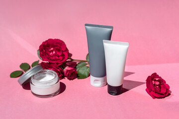 Bottle, tube, jar of cream or lotion with pink roses and on a pink background. Organic cosmetic. Treatment spa beauty skincare healthcare. Brand commercial. Product. Mock up cosmetics
