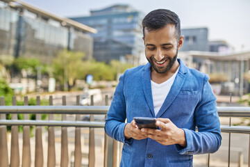 Portrait of smiling Indian arabic business man typing on mobile phone